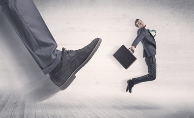Big foot in a black shoe fire small, young, businessman who is flying away in the space
