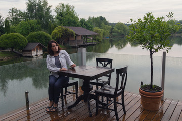 Woman at a cafe table by the pond. People