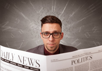 Young smart businessman reading daily newspaper with alphabet letters above his head