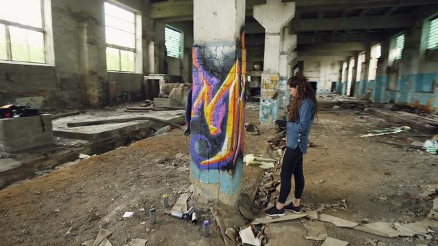 Time-lapse of graffiti artists are using aerosol paint to decorate abandoned industrial building with modern graffiti images. Creativity, street art and people concept.