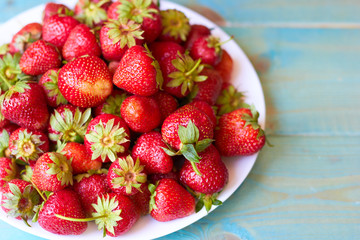 A plate of strawberries on a wooden table.