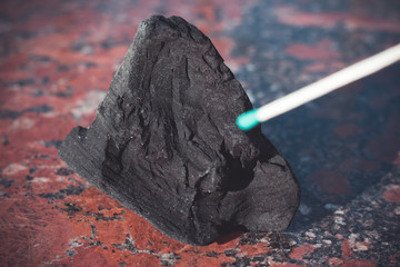 coal on a granite stone and a match, close-up