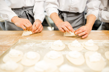 Workers forming raw buns with filling for baking at the manufacturing