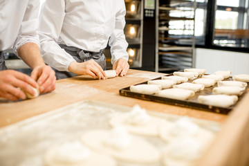 Workers forming raw buns with filling for baking at the manufacturing