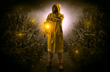 Fototapeta na wymiar Man in raincoat at night coming from thicket and looking something with glowing lantern 