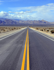 Driving on the open road in the desert with mountain backdrop