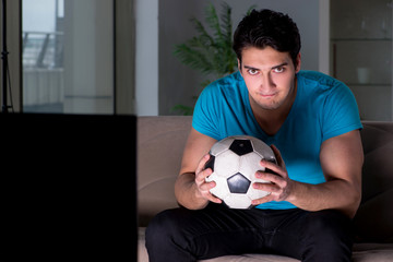 Young man watching football late at night