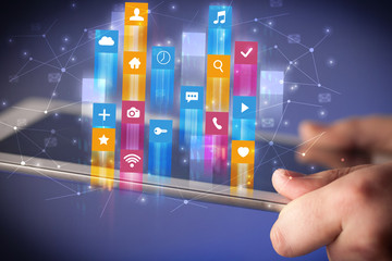 Businessman hand using tablet with flying application icons around
