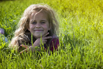 Little girl in spring grass with a smile on her face