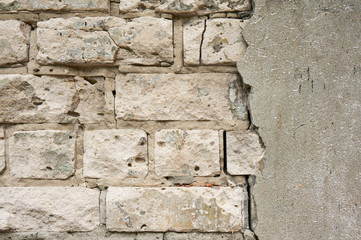 The old wall of white brick with a broken, cracked plaster. Abstract background.