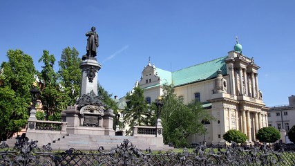 Fototapeta na wymiar Monument of polish poet Adam Mickiewicz and Carmelite church at Krakowskie Przedmiescie street in Warsaw, Poland.
