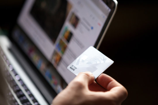 Close up view of male hand holding credit card buying doing internet shopping, customer making secure payment concept on laptop via e-banking web service, video blogger earning money online