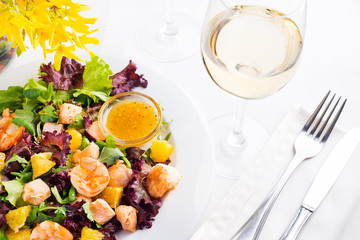 Healthy salad with prawns, lettuce, oranges and mango served on a plate with orange mustard sauce