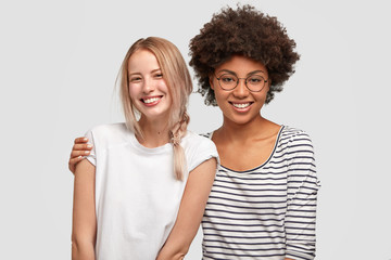 Two beautiful mutiethnic delighted women have good relationship and truthful friendship, embarce each other and smile gladfully, happy to meet after long time. Interracial friendship concept