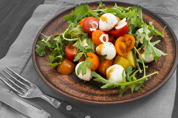 Rocket salad, tomatoes, mozzarella - traditional italian cuisine salad. Closeup.