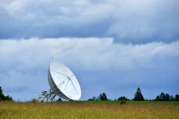 Large satellite dish in the field for receiving and transmitting tv signal and data transfer to the satellite, teleport