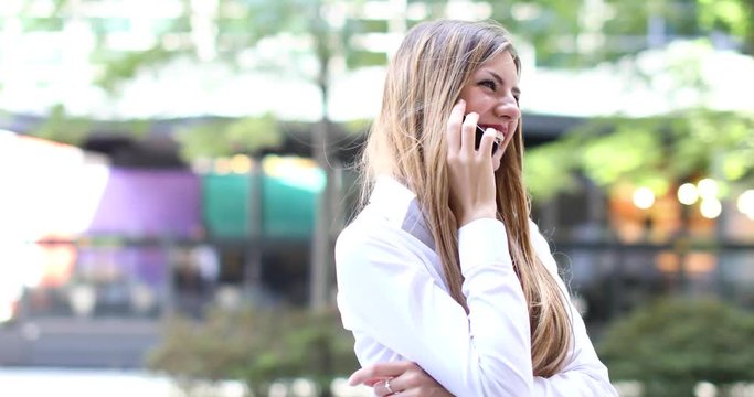 Cheerful young woman on the phone outdoor in a modern urban setting, laughing and looking happy