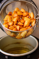 Freshly fried young potatoes from the fryer. Tasty potatoes fried on oil.