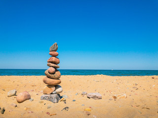 Fototapeta na wymiar Stones in the pyramid stand on the sandy sea beach