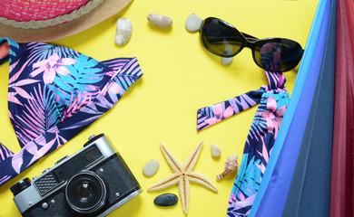 Yellow travel concept for sea or beach. Old vintage camera, Bikini top, seastar. Flat layout summer.
