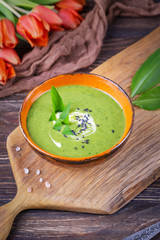 Homemade cream soup with wild leek on a wooden background. Rustic style