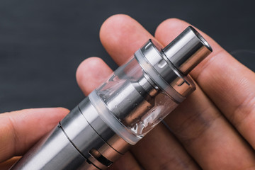 vape device at cloud of vapor background. Man hand shows