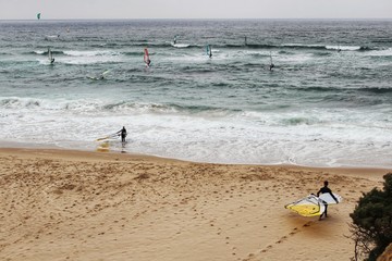 Surfers at Guincho beach under cloudy sky in Portugal