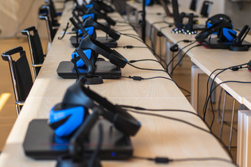 Close up of many virtual reality (VR) sets  in a classroom - headset, controller and computer. Gamer space, innovation or modern education concept.