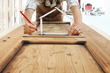 woodwork concept, carpenter with the meter makes the shape of a house