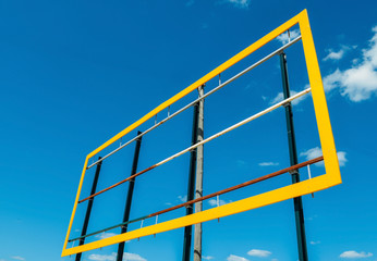 Blank billboard with yellow frame against a blue sky background