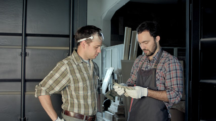 Two carpenters count money in workshop.