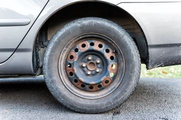 Closeup of tire wheel with missing cap cover on parked car, rust, hubcap