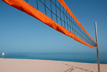 A beach volleyball net on the beach with a clear and sunny sky