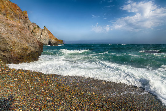 Sea waves crashing on the shore and flowing above seashore pebbles