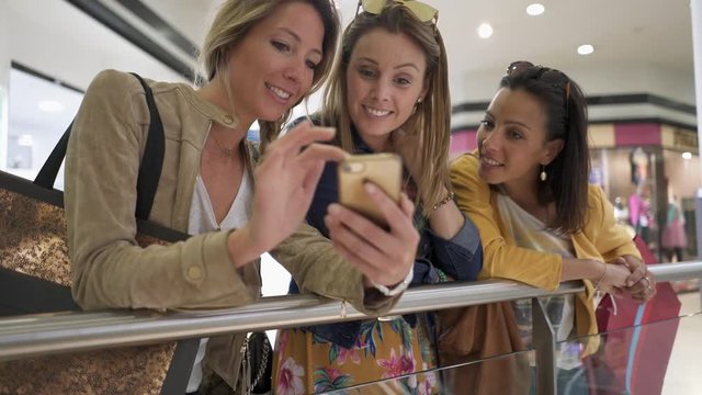 Girls in shopping mall using smartphone