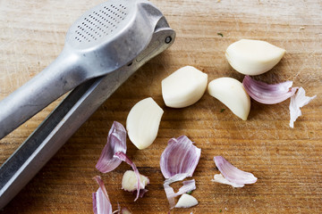Fototapeta na wymiar Peeled garlic cloves with garlic press