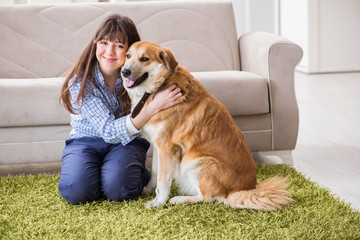 Happy woman dog owner at home with golden retriever