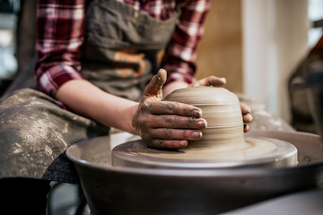 Female potter making clay pottery on a spin wheel.