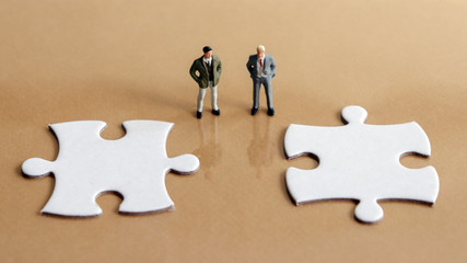 Two miniature men and two puzzle pieces.