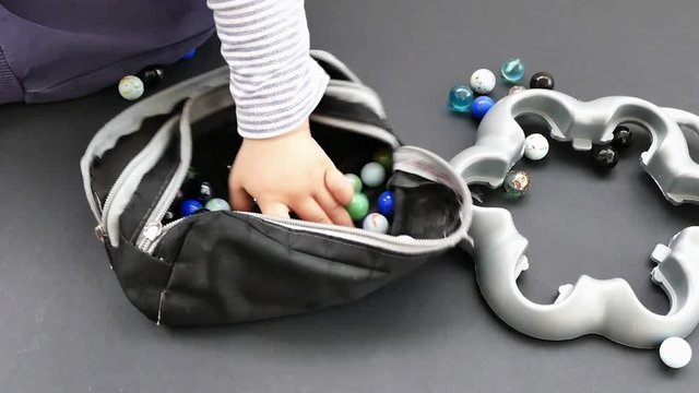 a baby is playing with glass marble,glass marble, colored on black ground,

