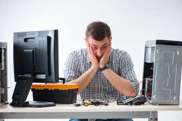 Young technician repairing computer in workshop