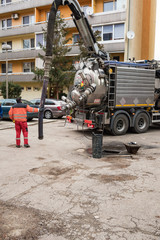 Man in boilersuit is pumping sewage with drainage suction sewage truck
