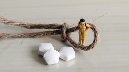 A miniature woman in the middle of a tied rope and drug.