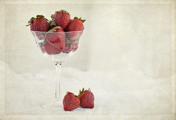 Textured photograph of crystal stemware filled with fresh strawberries