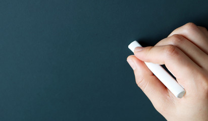 Naklejka premium Green chalkboard with hand holding white chalk.