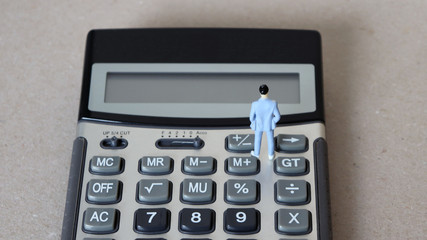 A miniature man standing on the calculator.