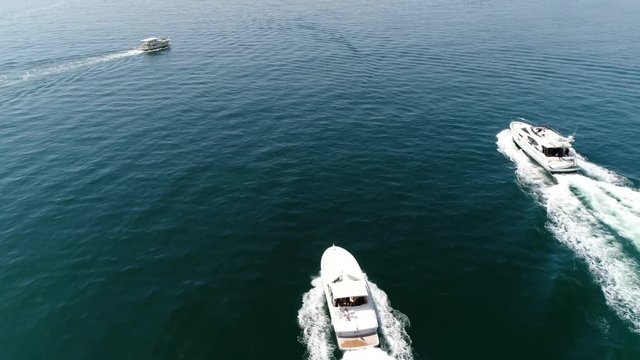 Aerial footage overtaking motorboats fitted with inboard engines and moving right next to each other showing the bright blue water and the bright white trail of the engines propelling the vessels 4k