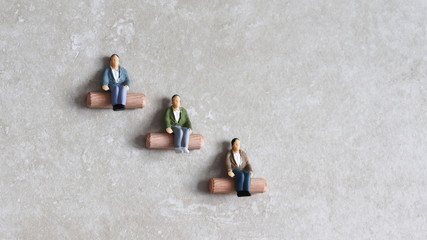 Miniature people sitting at different heights. Concept of job discrimination.