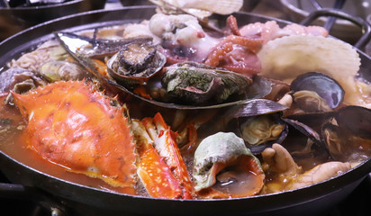 A hot spicy seafood stew boiling in a pot.