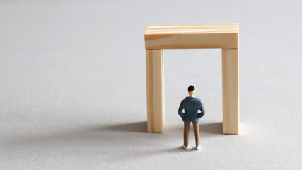 A miniature man who worries in front of a small entrance.